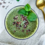 Bright green mint chocolate smoothie from overhead with mint leaves