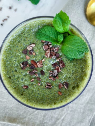 Bright green mint chocolate smoothie from overhead with mint leaves