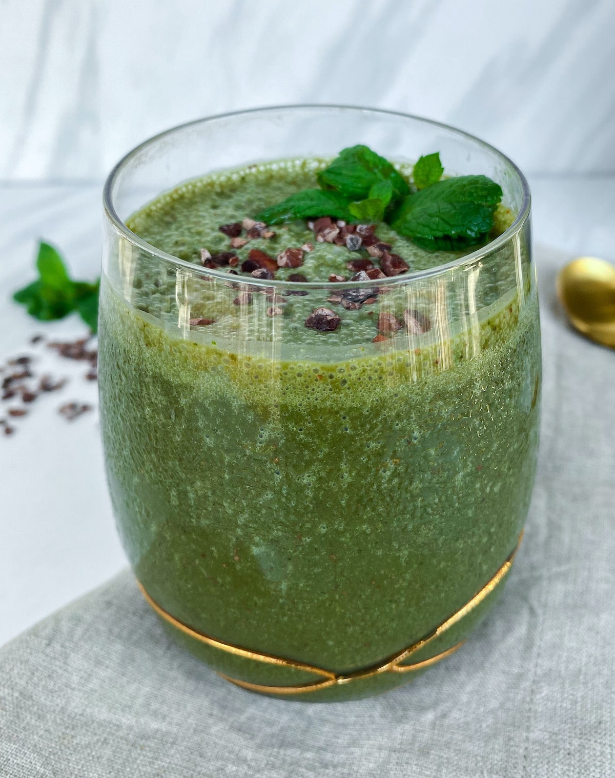 Bright green mint chocolate chip smoothie in a glass