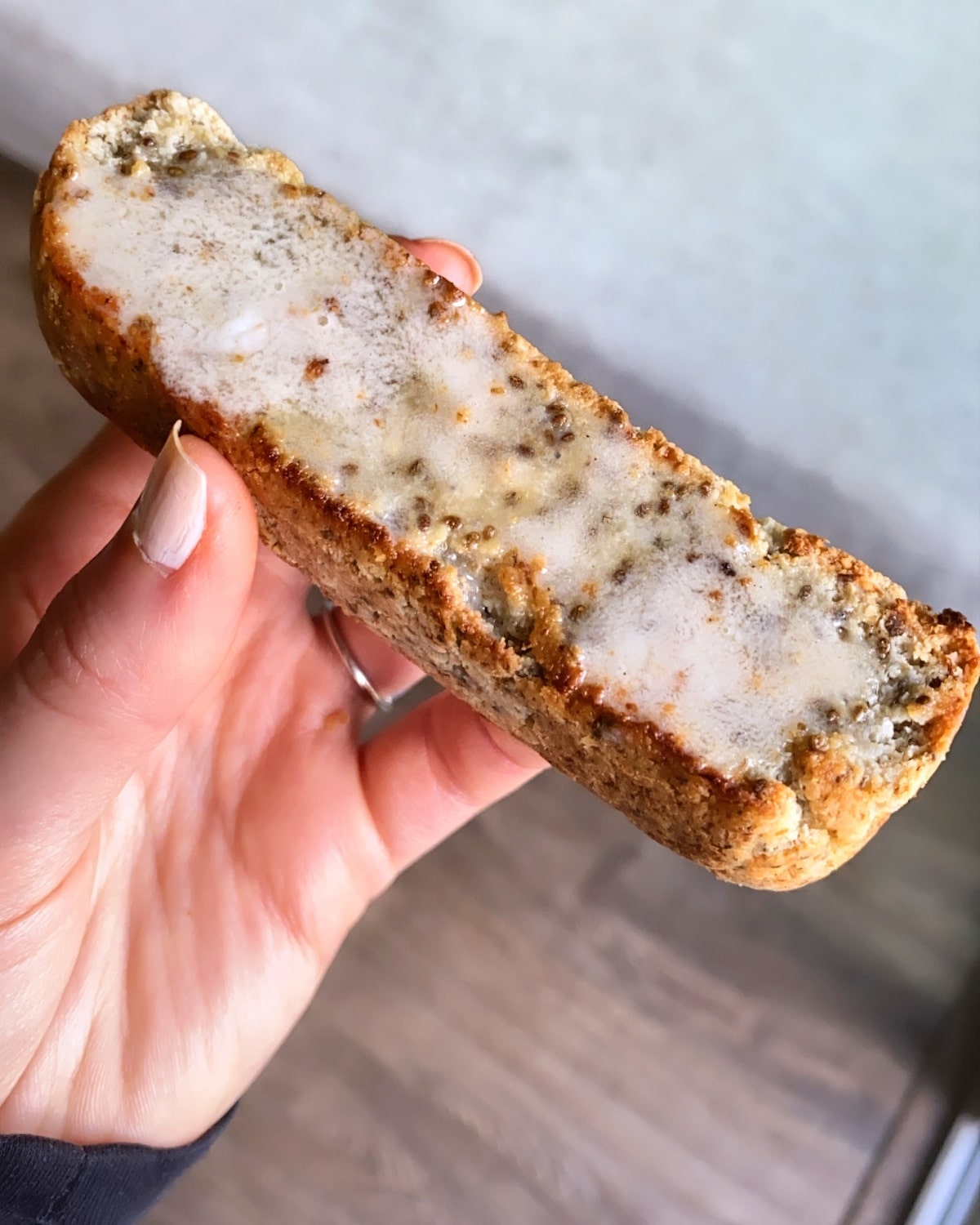 Holding homemade high fiber classic chia grain-free bread slice with butter melted on top
