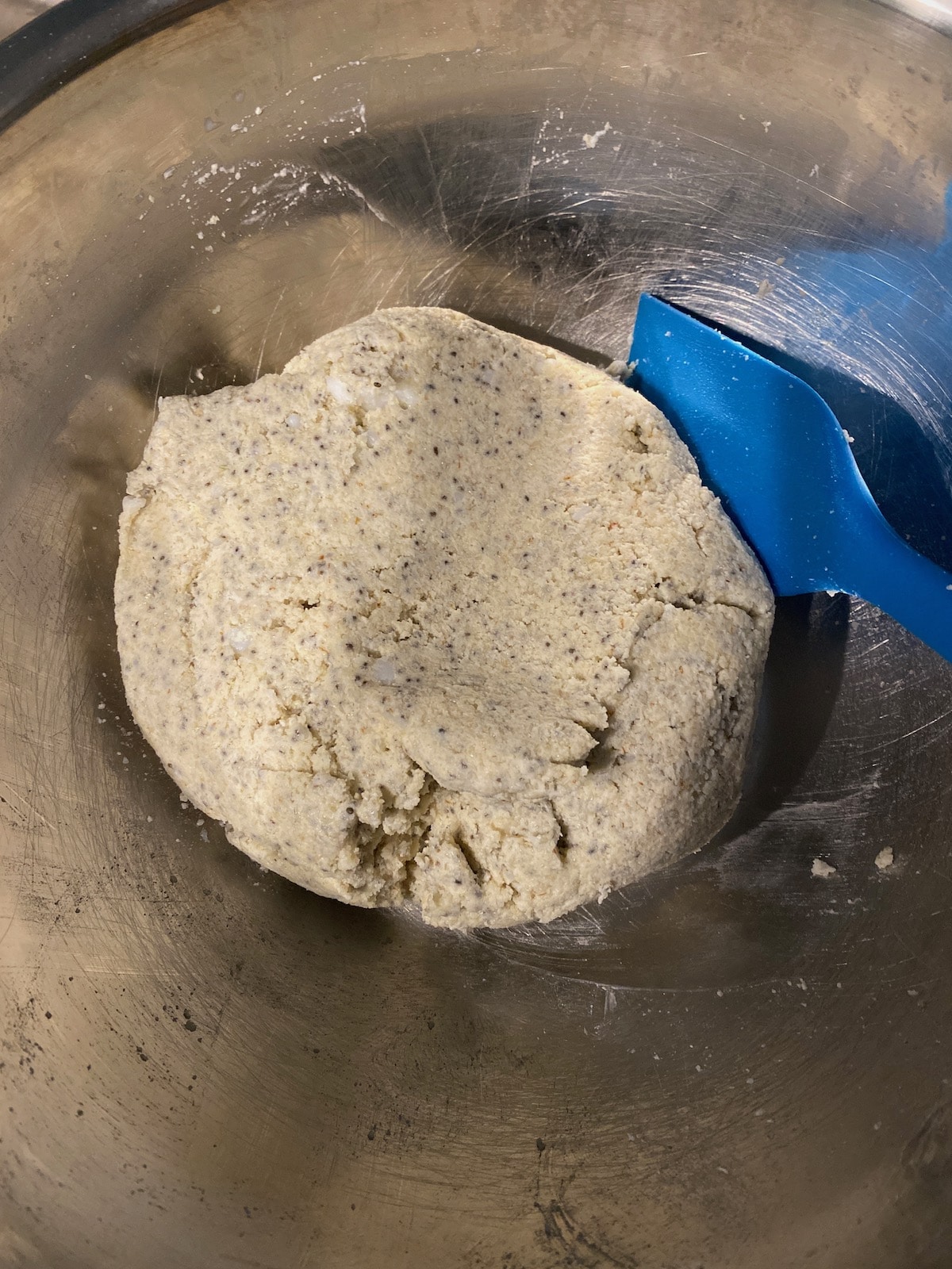 Homemade high fiber grain free bread dough in metal bowl with blue spatula