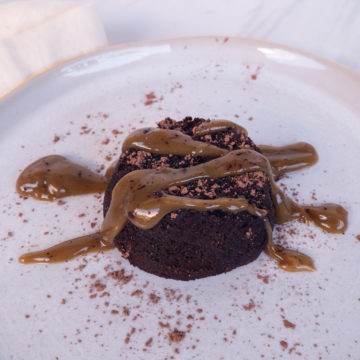 chocolate lava cake on white plate with golden drizzle