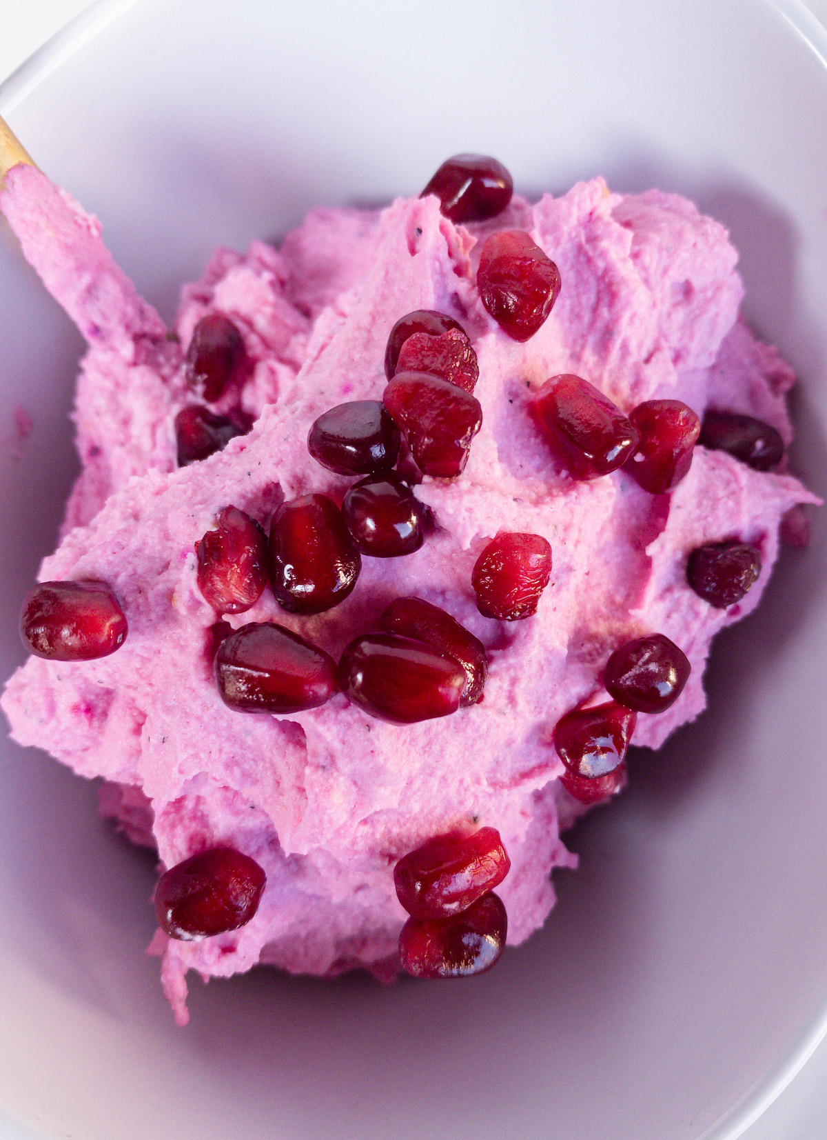 pink whipped cream with pomegranate seeds in a white bowl