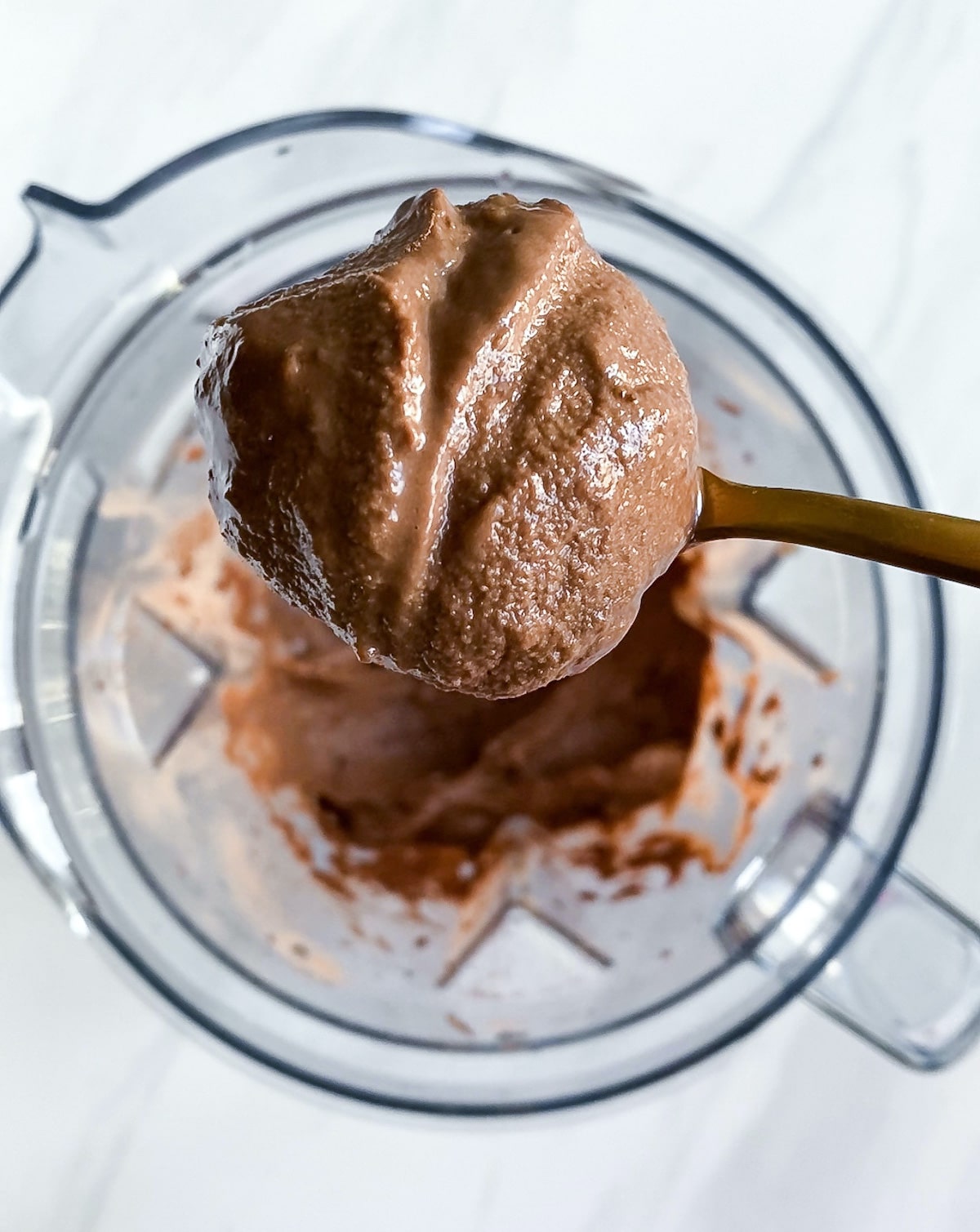 Spoon scooping vegan chocolate ice cream out of blender