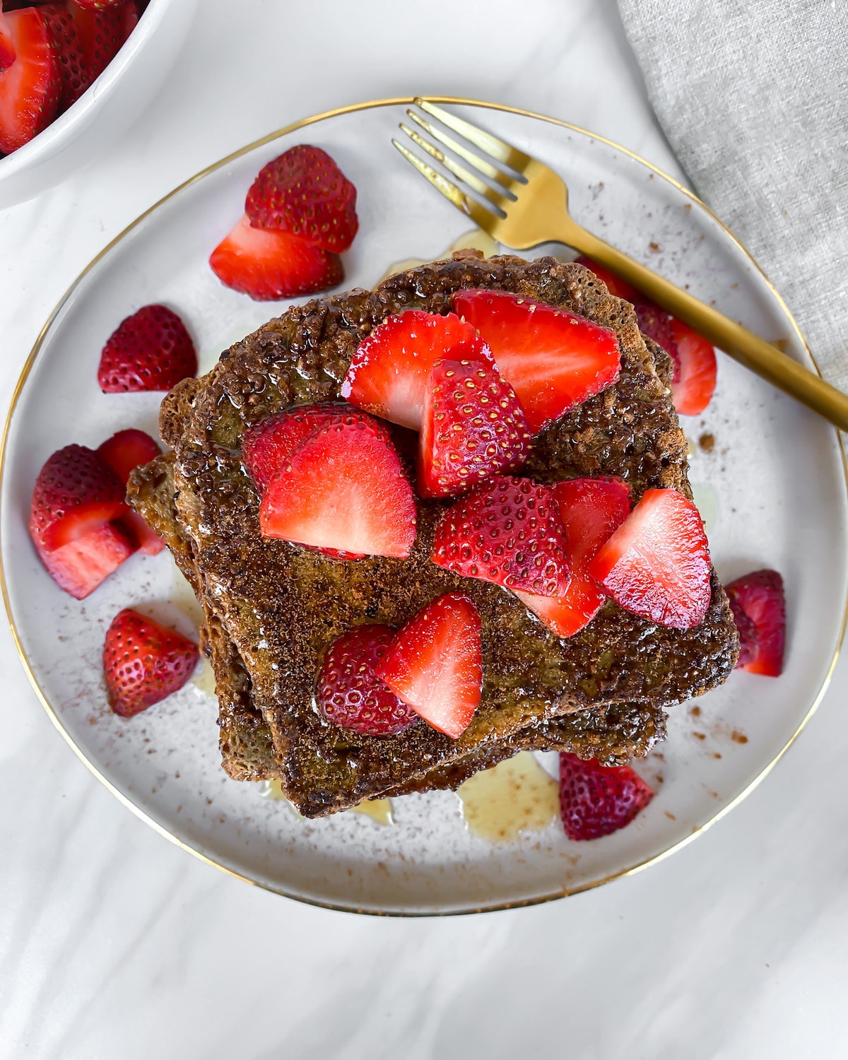 Healthy vegan gluten free golden brown french toast with bright red strawberries on top