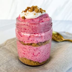 Layered strawberry cheesecake dessert in a glass jar