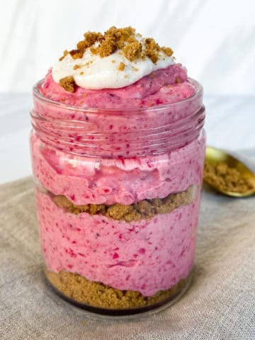 Layered strawberry cheesecake dessert in a glass jar